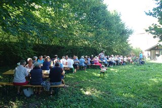 Mitglieder und Gäste des VdK sitzen an Biertischen beim Grillfest im Garten des Rauenberger Winzermuseums.