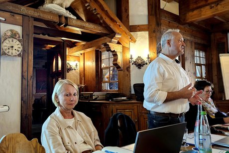 Herr Metzger stehend vorne er&ouml;ffnet die Sitzung Edeltraud Guse sitzt daneben und bedient Laptop und Beamer.