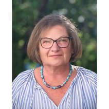 Frau mit Brille und blau-grauer Halskette, in blau-weiß-gestreifter Bluse.