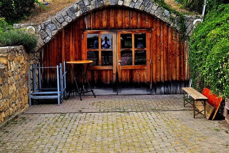 Der Gew&ouml;lbeeingang im Berg mit einer Holzfasade mit Fenster und T&uuml;r.