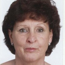 Frau mit braunen Haaren und zwei Perlen Ohrringe.