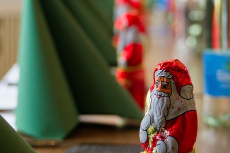 Tischdeko bei der Weihnachtsfeier: gr&uuml;ne Servietten und rote Schoko-Nikol&auml;use