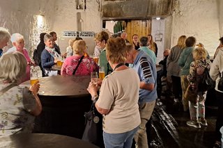 Bild zeigt die Gruppe bei der Bierverkostung im Keller um alte Bierbotiche stehen