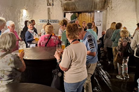 Bild zeigt die Gruppe bei der Bierverkostung im Keller um alte Bierbotiche stehen