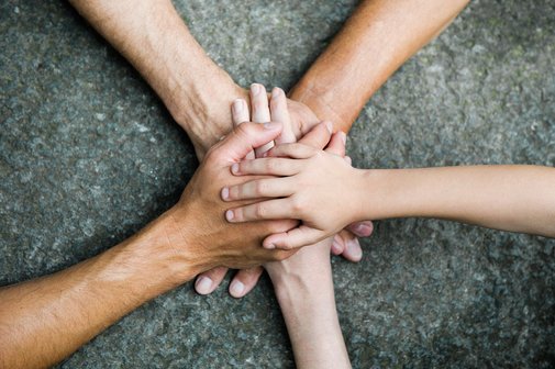 Fünf Personen legen jeweils eine Hand aufeinander, so dass ein Kreis bzw. ein Stern entsteht