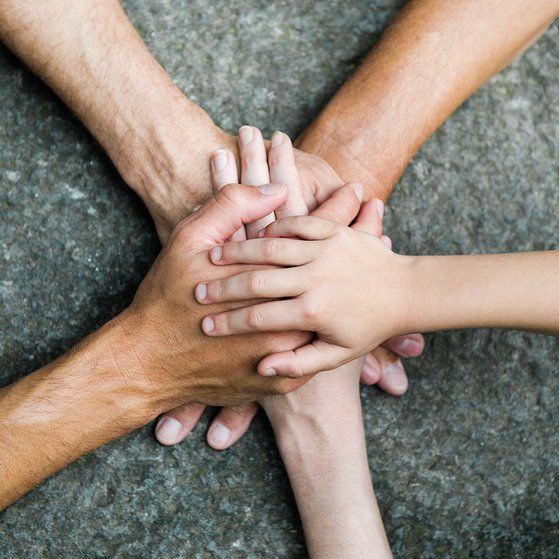 Hände zusammen für Gemeinschaft Fünf Personen legen jeweils eine Hand aufeinander, so dass ein Kreis bzw. ein Stern entsteht