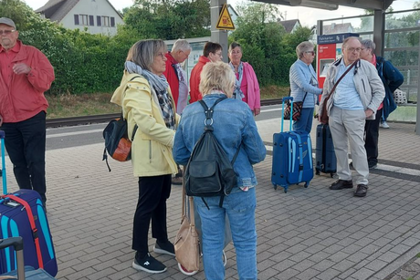 Bild zeigt Männer und Frauen an der Bushaltestelle auf den Bus warten