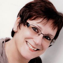 Frau mittleren Alters dunkler Haare mit Brille und einem L&auml;cheln