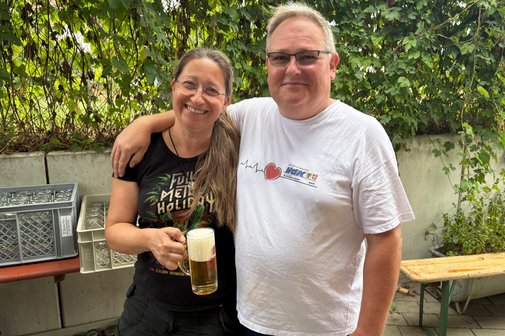Das Photo zeigt Martina Oberrauch und Arndt Minter lachend Arm in Arm mit einem frisch gezapften Bier in der Hand.