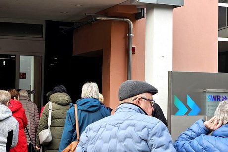 Mitglieder in Winterkleidung dr&auml;ngen sich durch den Eingang beim SWR