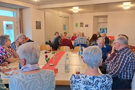 Teilnehmer beim Weißwurstfrühstück, an Tischen sitzend