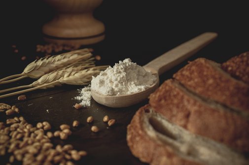 auf dem Tisch liegen Getreide, Mehl und mehrere Scheiben Brot