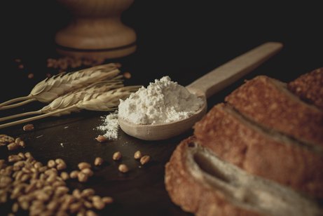 auf dem Tisch liegen Getreide, Mehl und mehrere Scheiben Brot