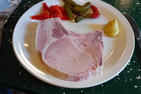 Bild zeigt einen Teller mit einem Rippchen mit Senf und Gurgen