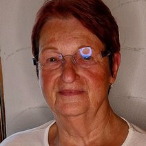 Gisela Kienle l&auml;chelnd mit wei&szlig;em Oberteil, vor einer wei&szlig;en Wand.