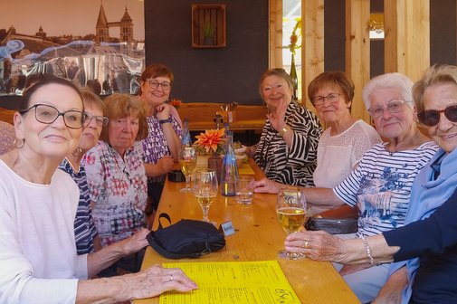 ESTiVAL Eine Gruppe von Frauen sitzt an einem Biertisch und lächelt freundlich in die Kamera.