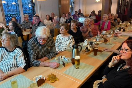 Mehrere Personen sitzen um gedeckte Kaffeetafeln