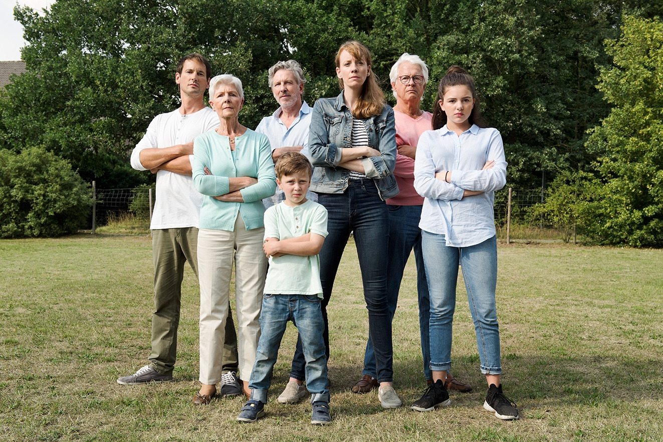 Eine Gruppe von Menschen unterschiedlichen Alters frontal stehend und mit verschränkten Armen