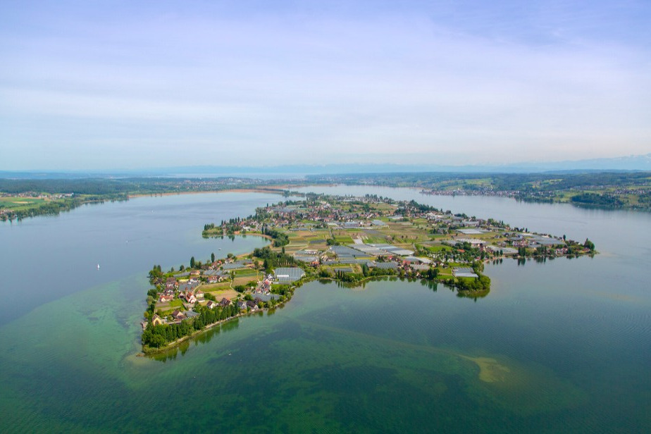 Luftaufnahme der Insel Reichenau im Bodensee mit landwirtschaftlichen Flächen, Gewächshäusern und Siedlungen am Ufer