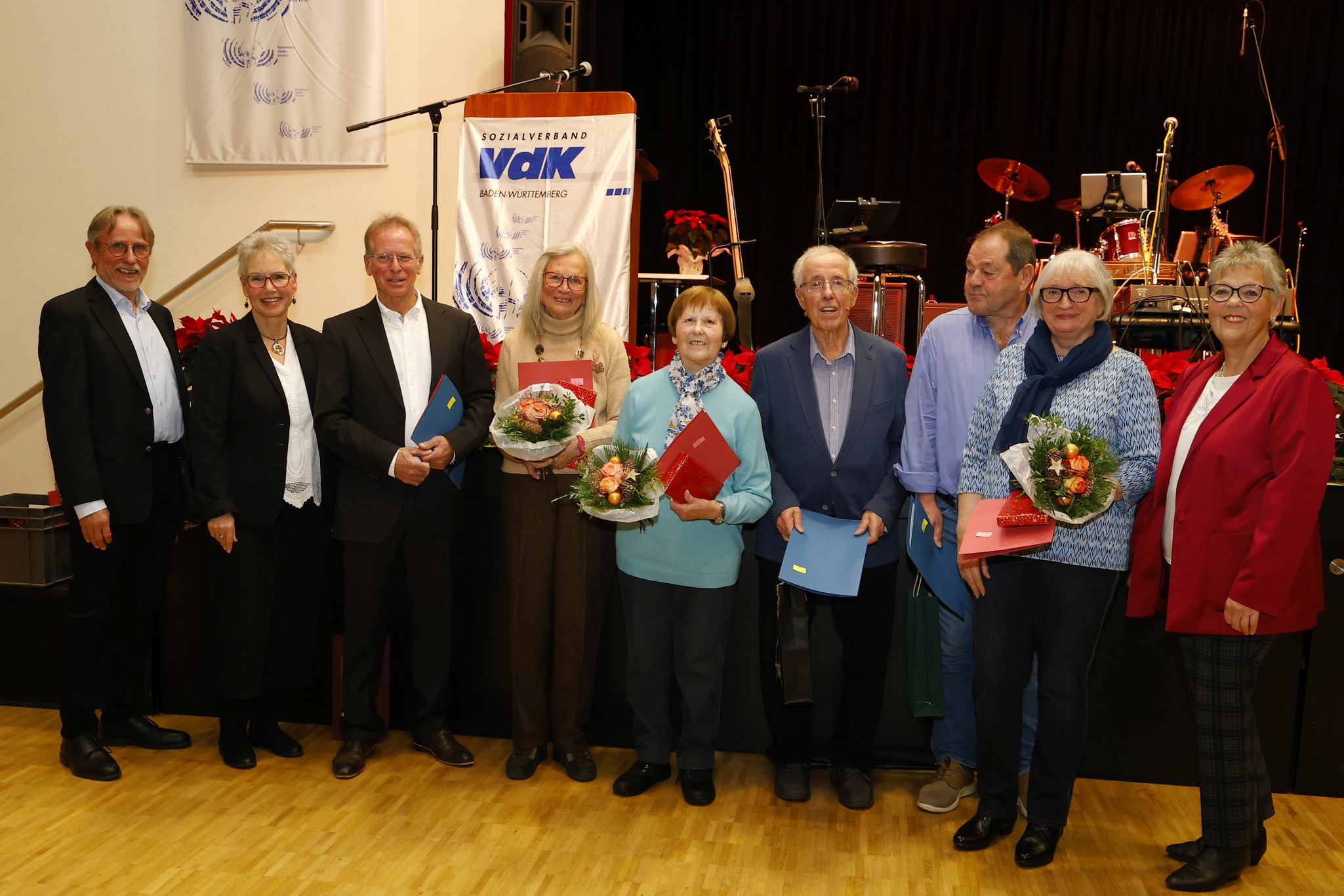 Gruppenbild mit den geehrten langj&auml;hrigen VdK Mitgliedern, im Hintergrund Renerpult mit VdK Flagge