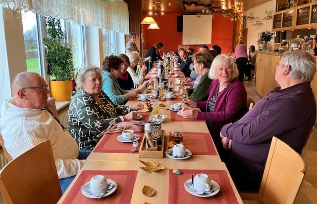 Mehrere Personen sitzen um eine gedeckte Kaffeetafel