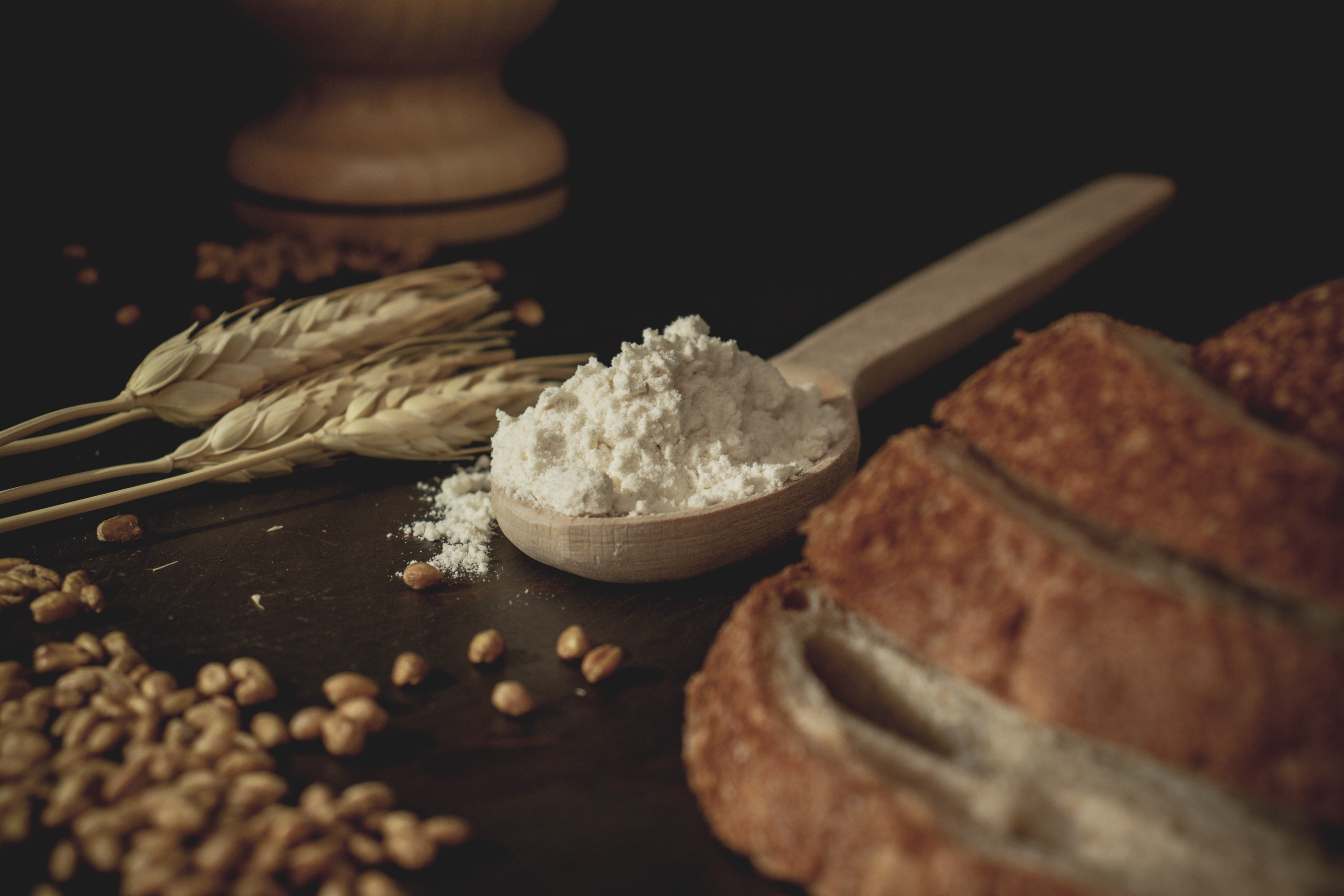 auf dem Tisch liegen Getreide, Mehl und mehrere Scheiben Brot