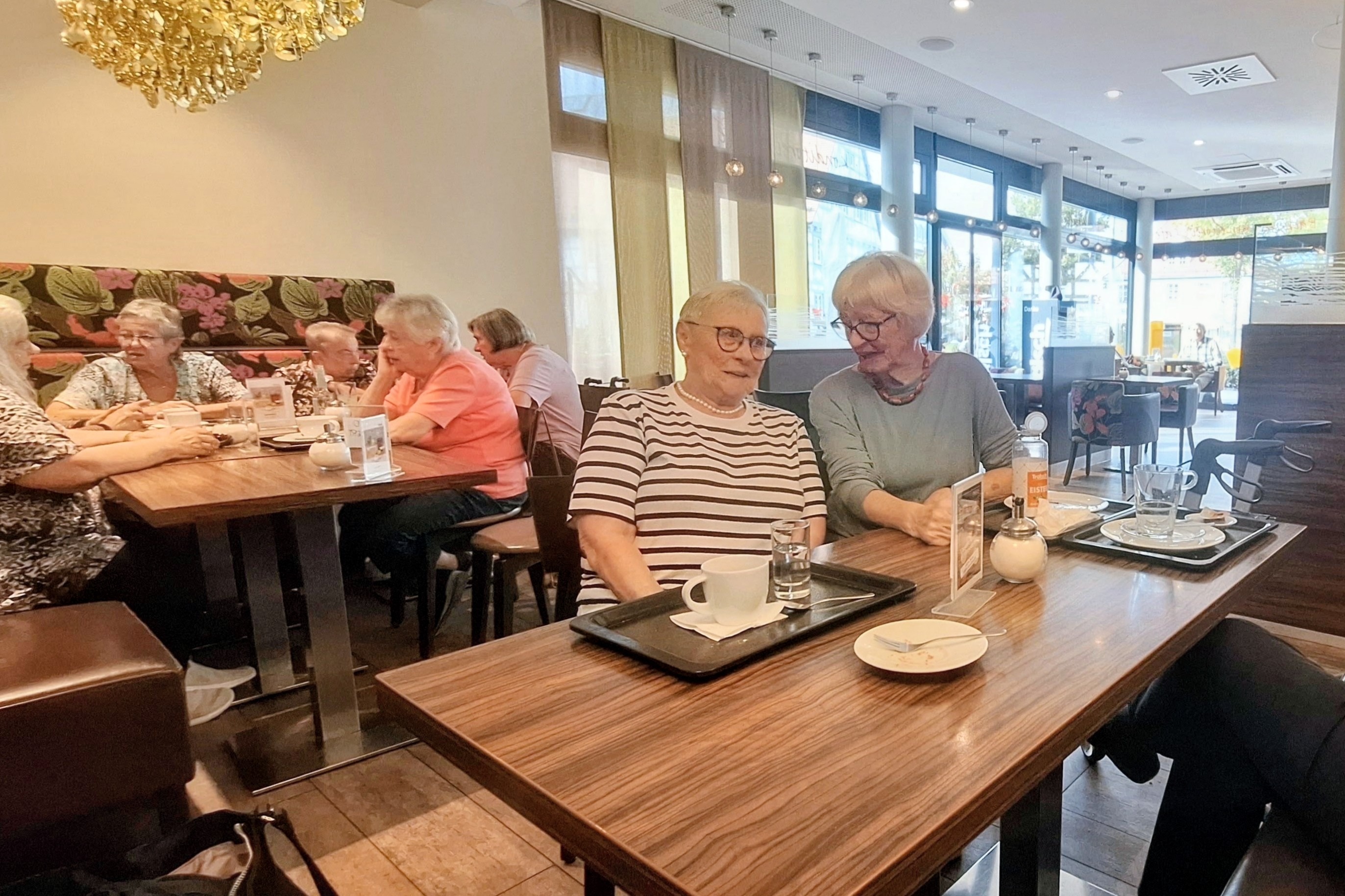 Es sitzen viele Mitglieder bei Kaffee und Kuchen an einem Tisch und unterhalten sich intensiv. Ein paar Mitglieder mussten den zweiten reservierten Tisch in Anspruch nehmen, da der Platz am ersten Tisch nicht f&uuml;r alle ausreichte.