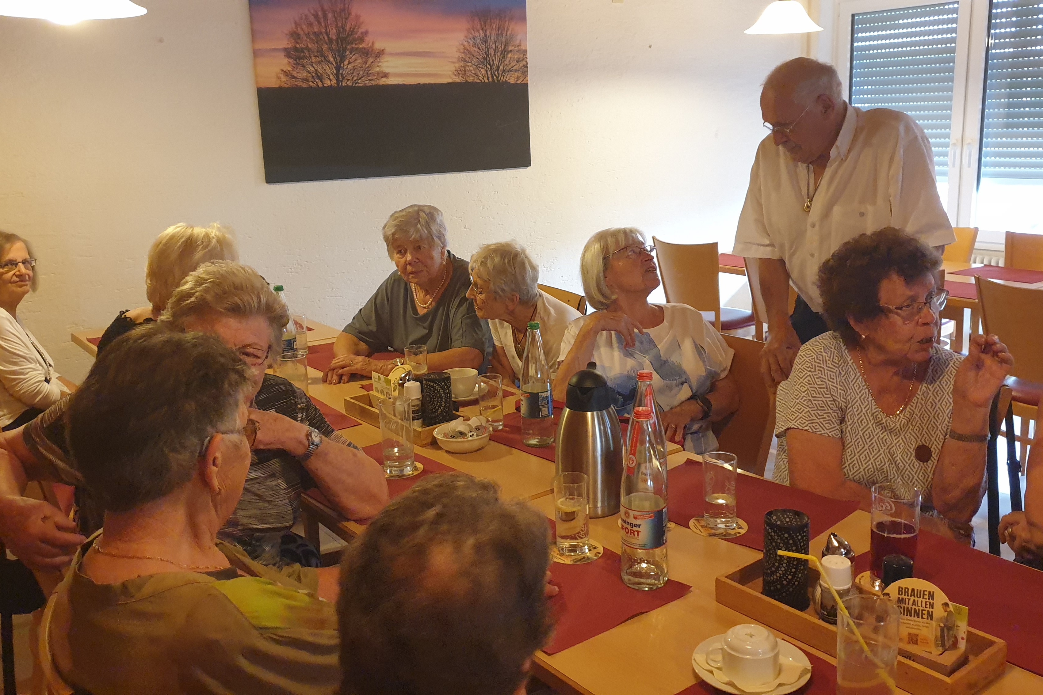 Mehrere Personen sitzen um eine gedeckte Kaffeetafel