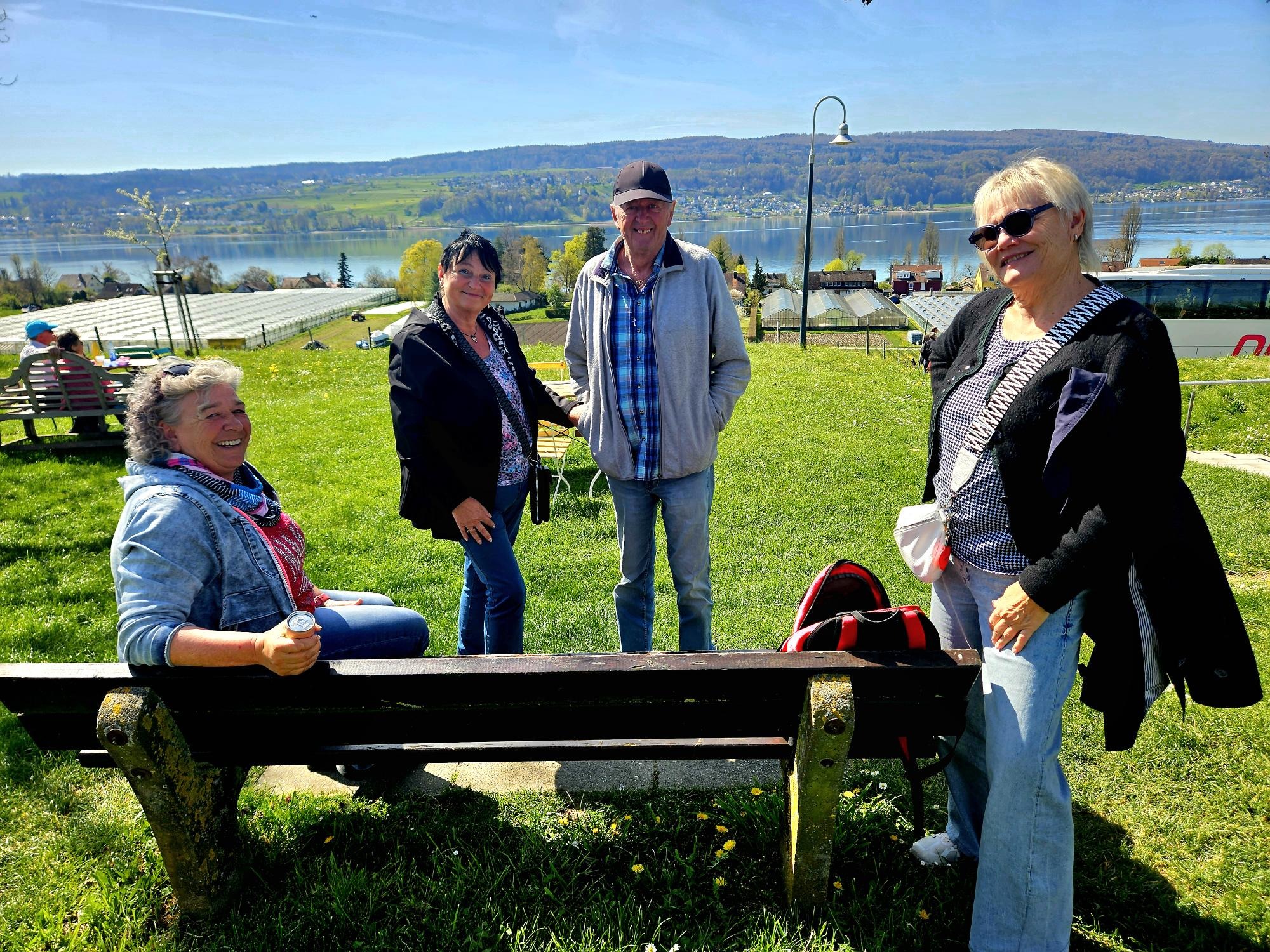 4 Mitglieder auf einer Wiese um eine Parkbank mit lachenden Gesichter.