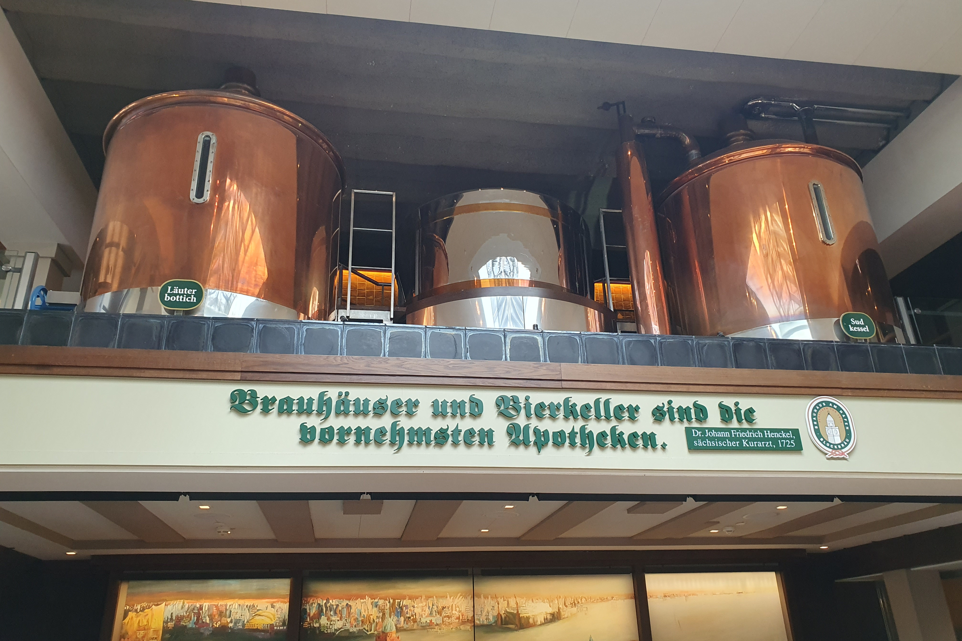 Zu sehen ist auf einer Empore zwei alte gl&auml;nzende Sudkessel im Brauhaus am Hafen in Hamburg. Davor ist ein Spruch in dunkelgr&uuml;n von dem s&auml;chsischen Kurarzt Dr. Johann Friedrich Henkel von 1725. Da ist folgendes zu lesen: Brauh&auml;user und Bierkeller sind die vornehmsten Apotheken.