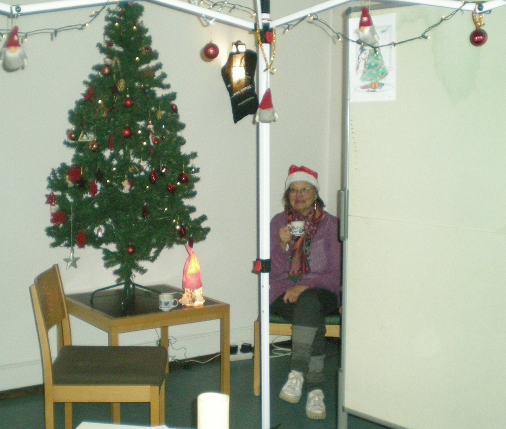 Ein VdK Mitglied innerhalb des Standes mit Weihnachtsbaum und einem warmen Getränk