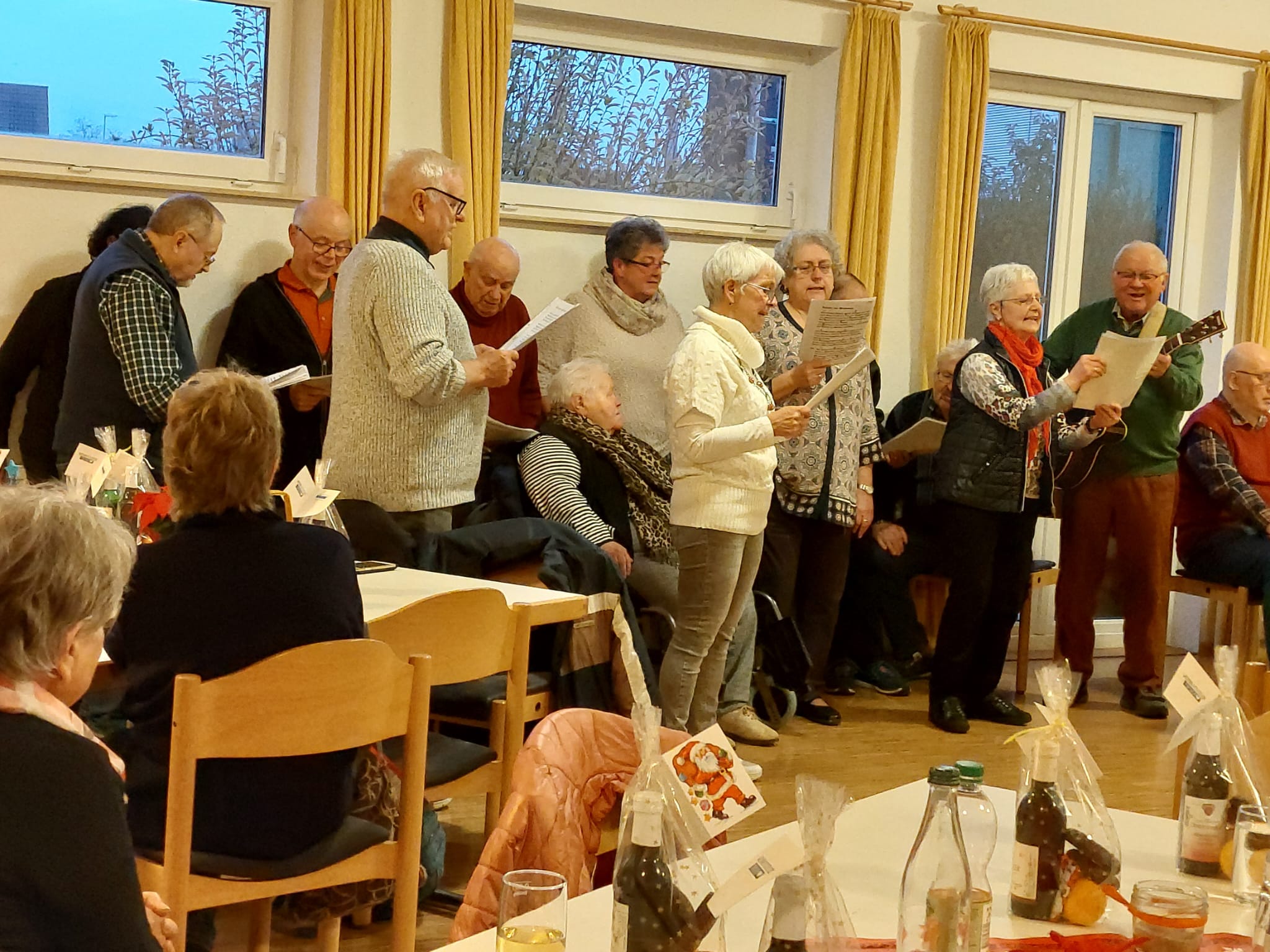 Männer und Frauen stehen in einer Halle und singen.