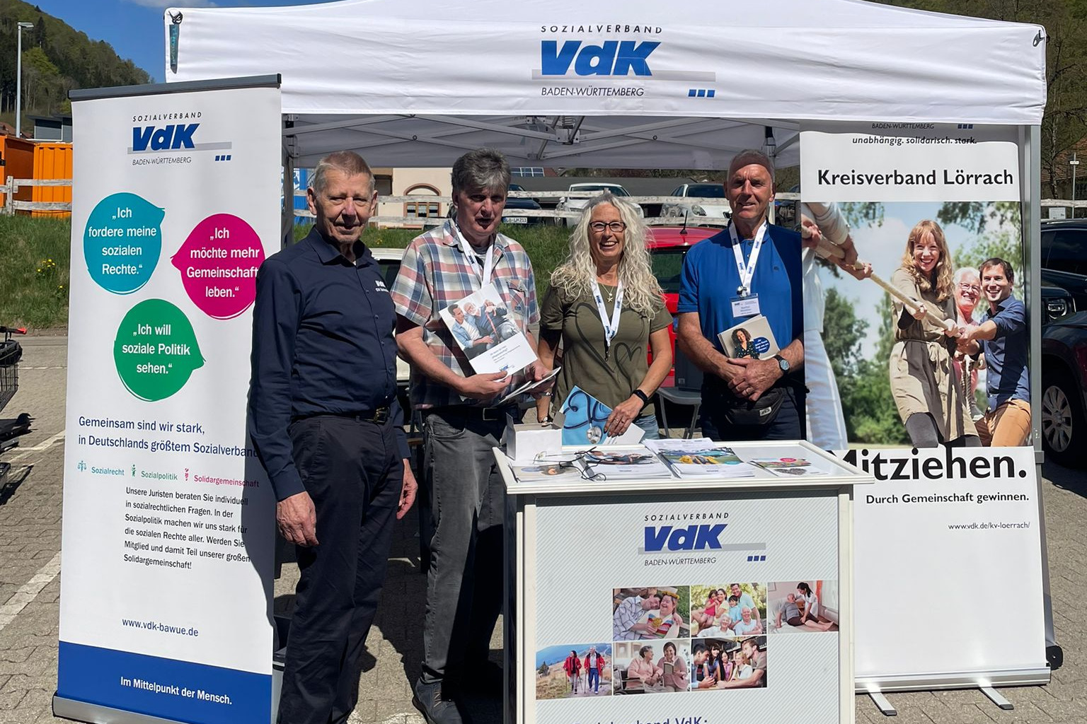 Hinter dem Infostand des VdK vom Kreisverband Erhard Sch&ouml;pflin, vom Ortsverband R&uuml;diger Hasberg und Angela Gutmann sowie der Kreisvorsitzende Manfred Merstetter unter dem Infozeltdach, rechts und links VdK Roll-ups