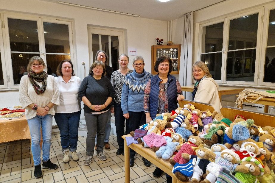 Das Foto zeigt unsere "Hoffnungsb&auml;ren" auf Tischen im Vordergrund. Im Hintergrund die fleissigen Strickerinnen und die Empf&auml;nger der B&auml;rchen