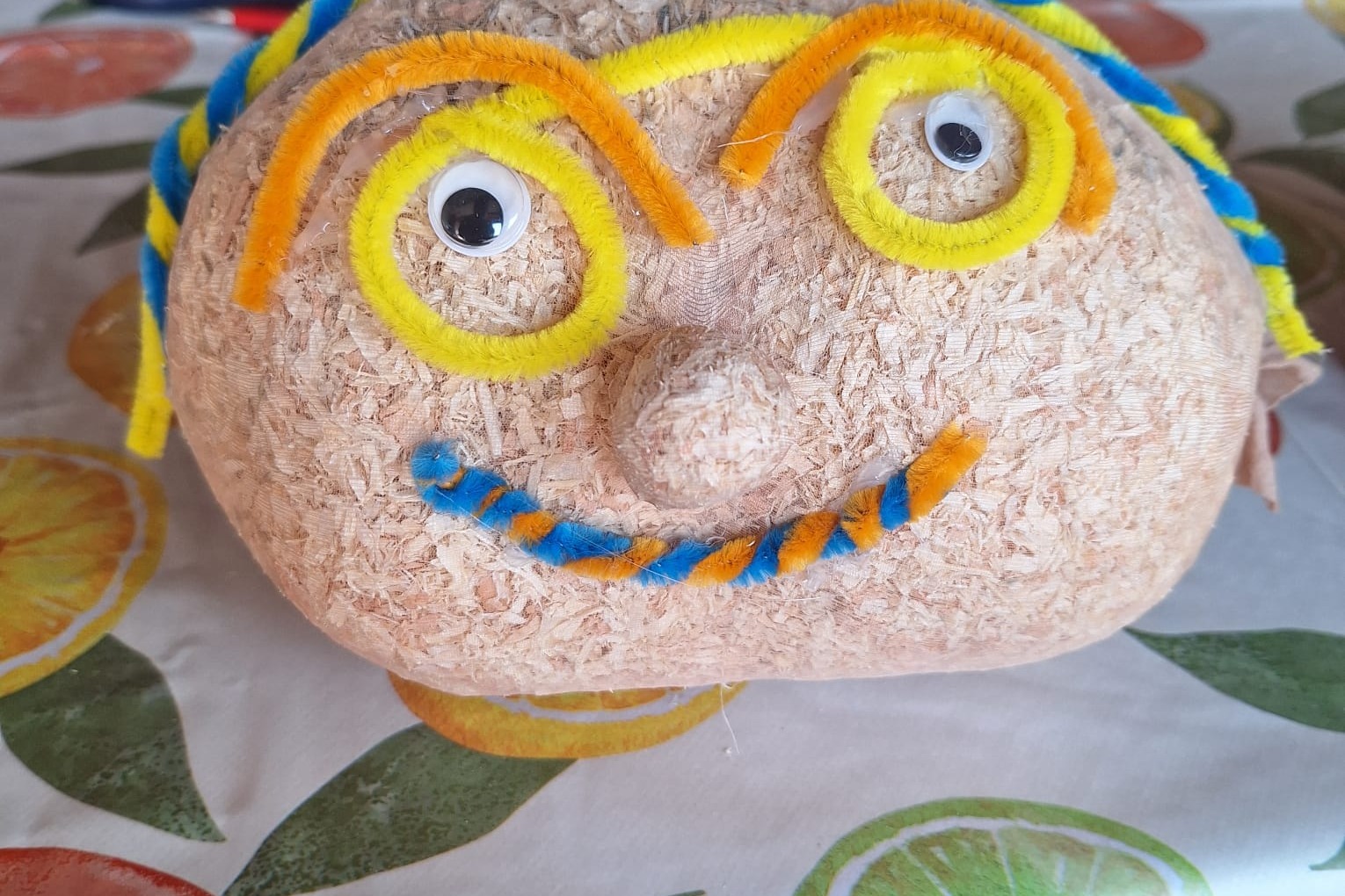 Kreativer Graskopf Ein Bild des sogenannten Kopfes: ein Feinkniestrupf, gefüllt mit Holzspänen und dekoriert mit bunten Pfeifenputzern