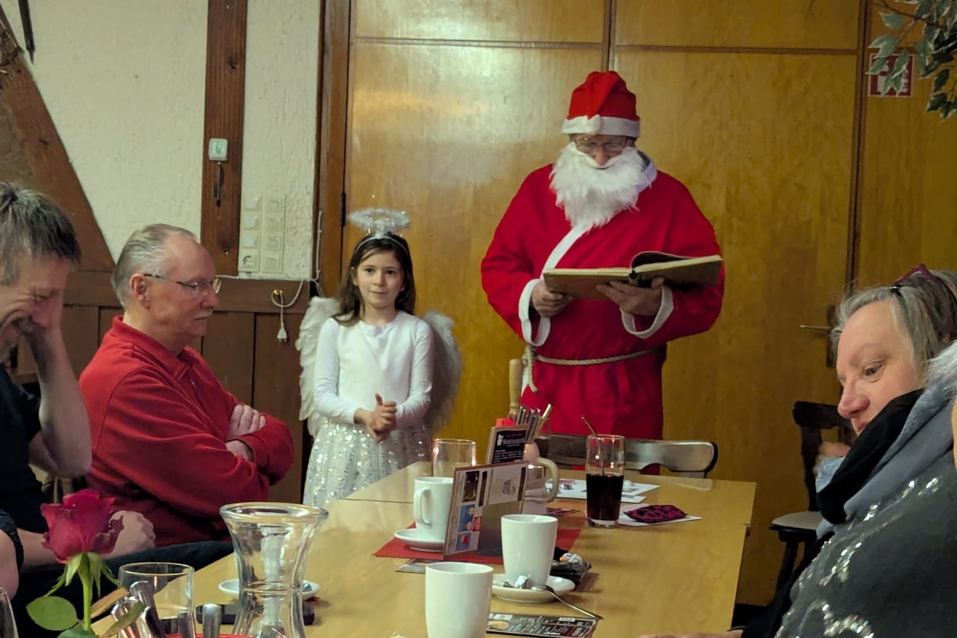 Der Nikolaus liest aus seinem goldenen Buch vor, mit dabei das Helfer-Engelchen Ida.