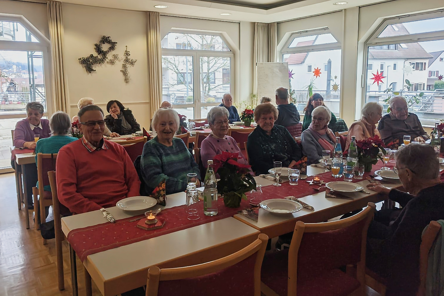 Panoramafoto des Festsaals mit mehreren Tischen, an denen vorwiegend &auml;ltere Menschen sitzen und sich angeregt unterhalten