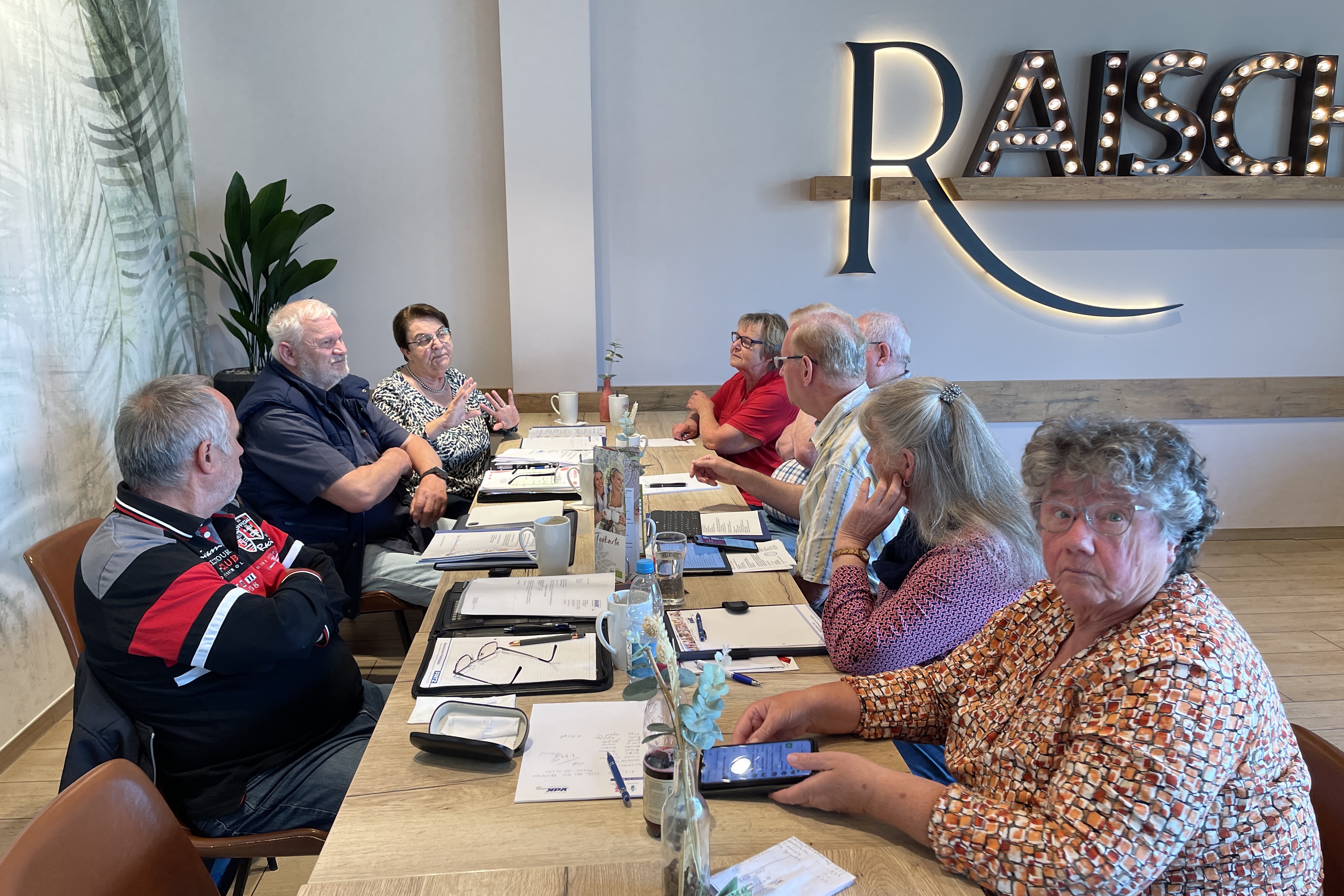 Personen sitzen am Tisch und unterhalten sich