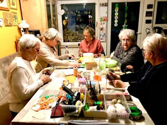 Gemeinsam macht das Basteln noch mehr Spaß Bastel- und Dekogruppe: mehrere Frauen sitzen an einem voll beladenen Tisch mit bunten Bastelutensilien und fertigen Basteleien zu Ostern